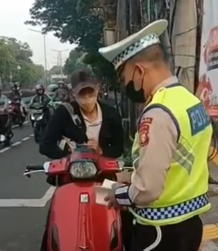 Petugas Kepolisian Melakukan Tilang Manual di Jalan